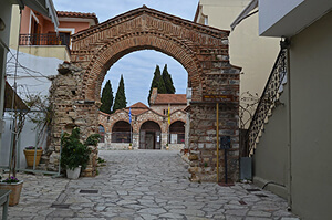 Modern procession through the Byzantine arched gateway to Saint Theodora church in Arta, Greece
